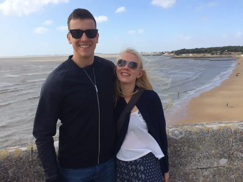 Tess and Jonny on the sea wall at Fouras, the beach behind them