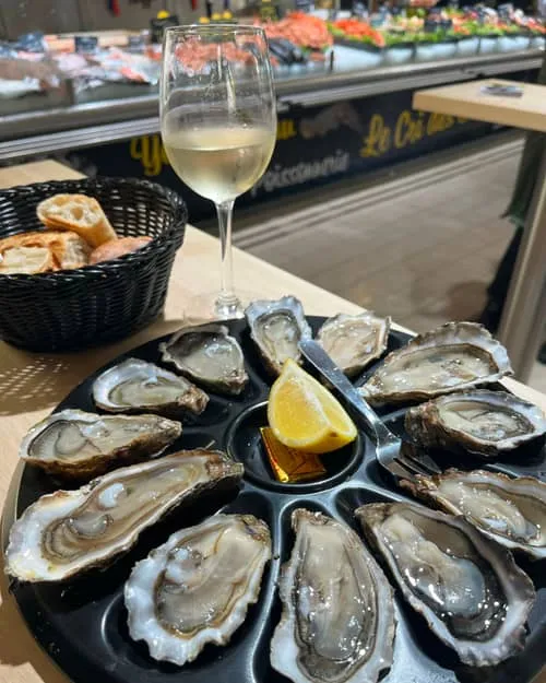 A dozen oysters and a glass of white at the fish counter in the market