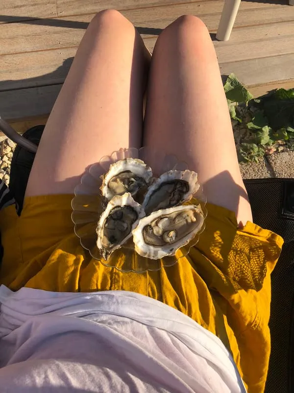 A plate of oysters balanced on a yellow dress