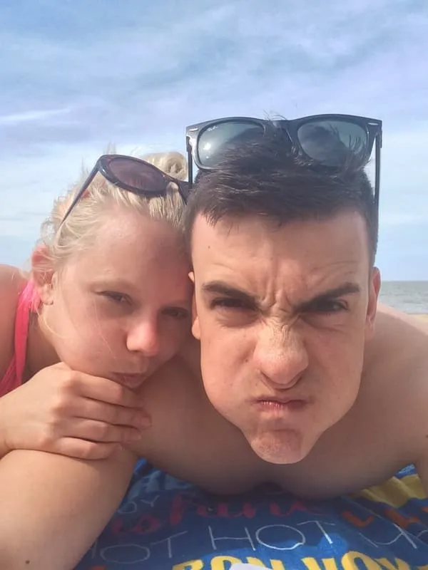 Tess and Jonny pulling faces at the camera on the beach