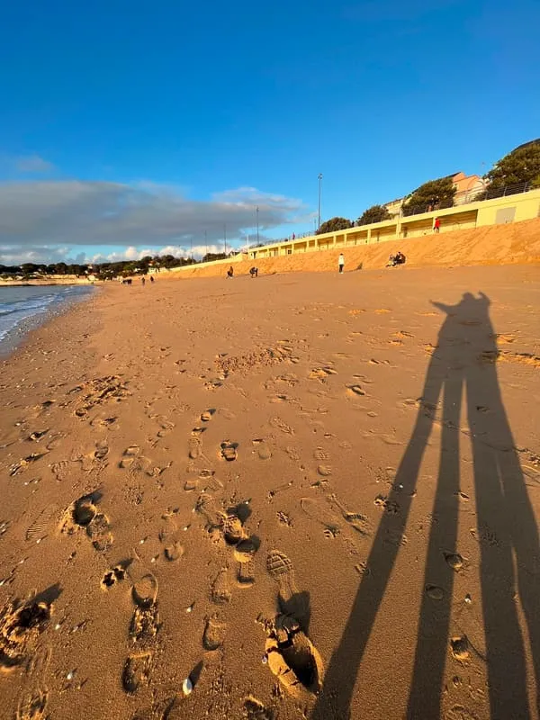 Two long shadows cast across the beach at golden hour